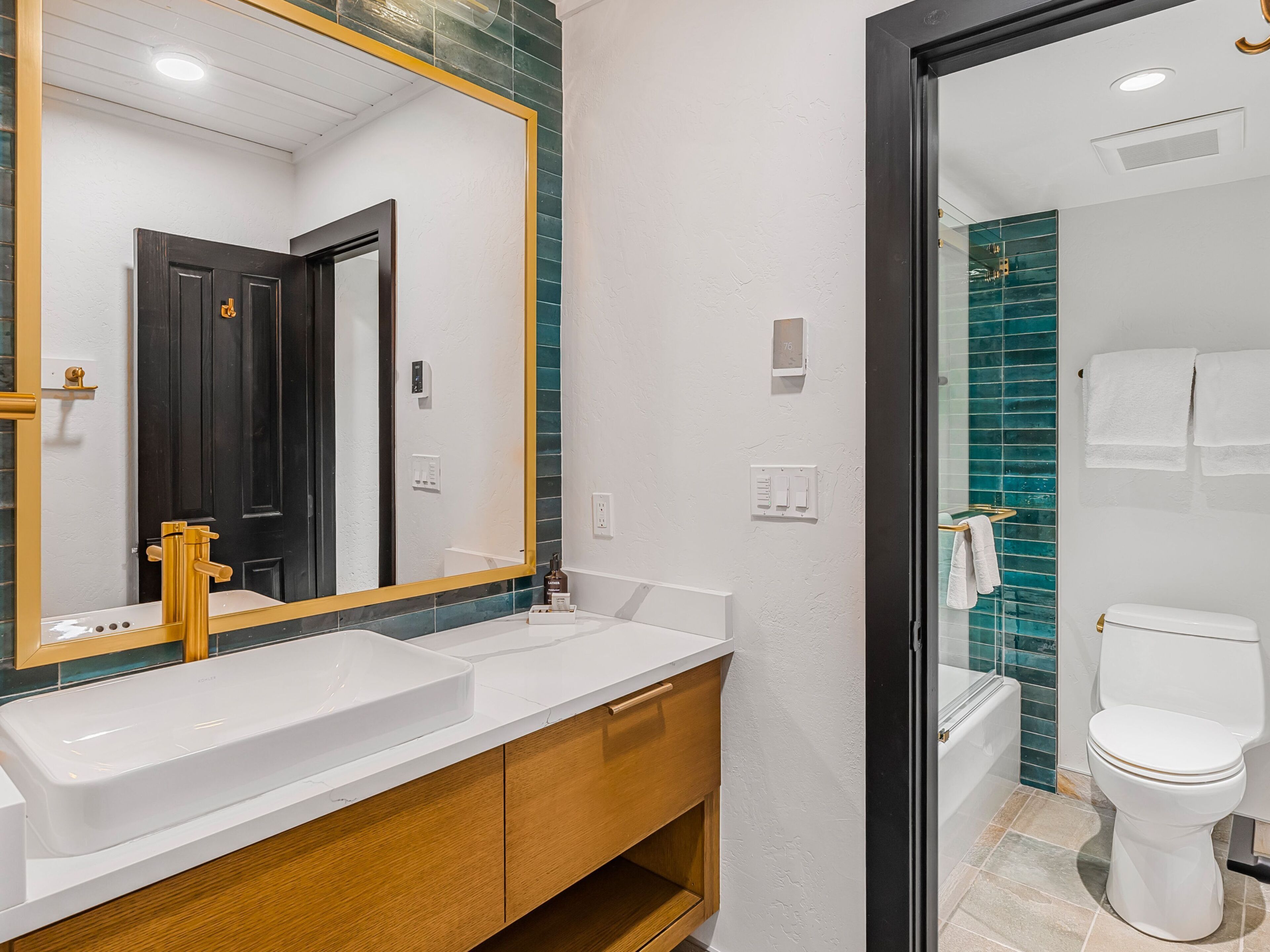 A modern bathroom with a white sink, wooden vanity, and a large mirror.