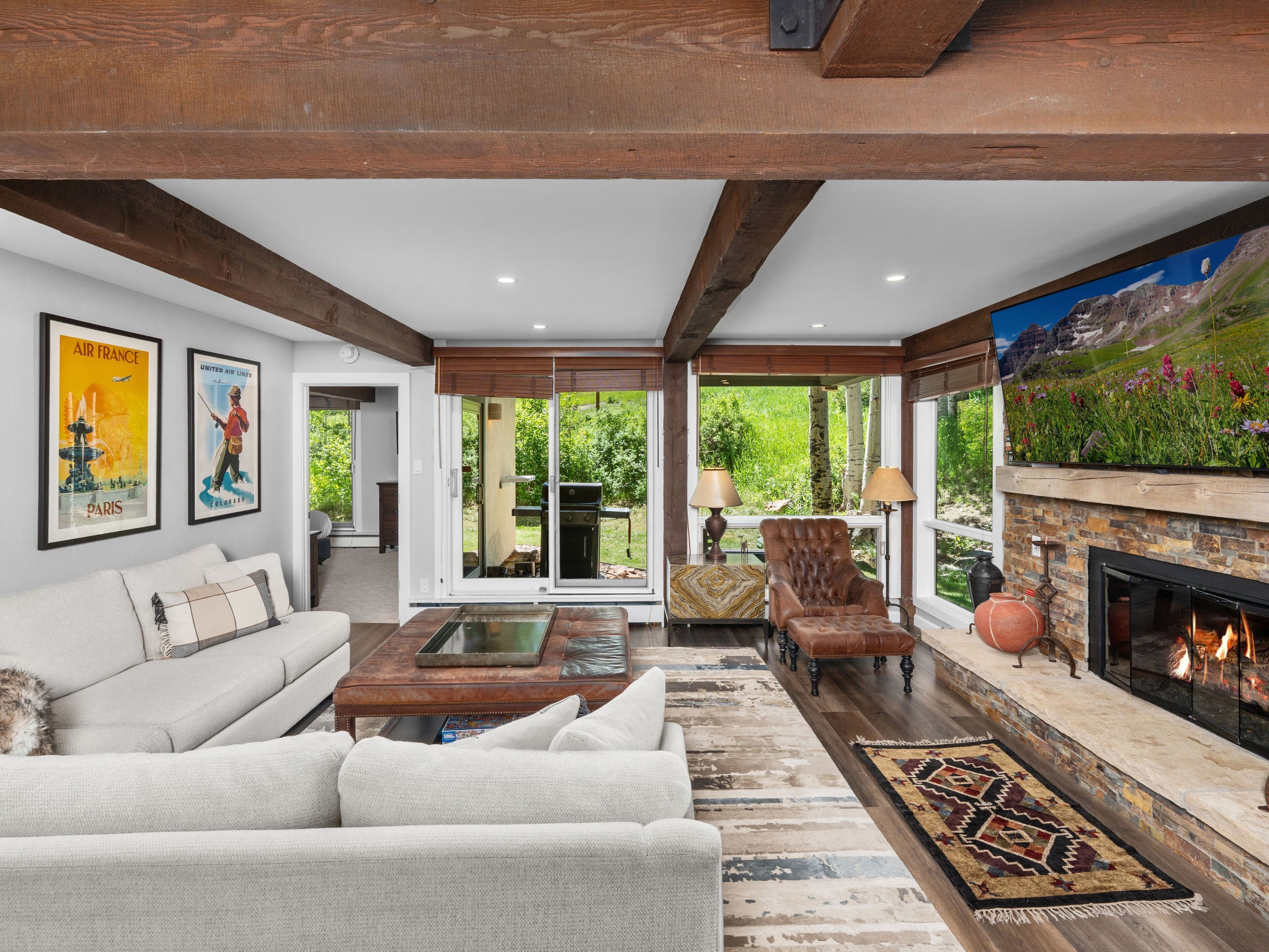 A spacious living room with a fireplace, a sofa, a coffee table, and a television mounted on the wall.