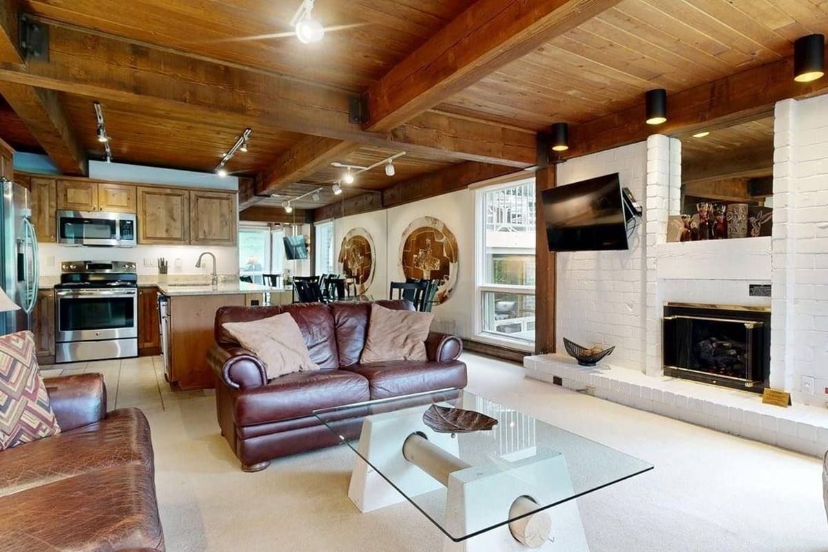 A modern living room with a leather sofa, glass coffee table, and a fireplace.