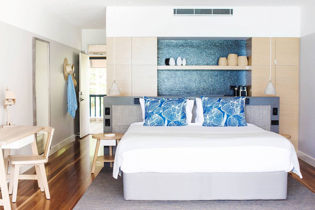 A modern bedroom with a large bed, wooden furniture, and a tiled backsplash.