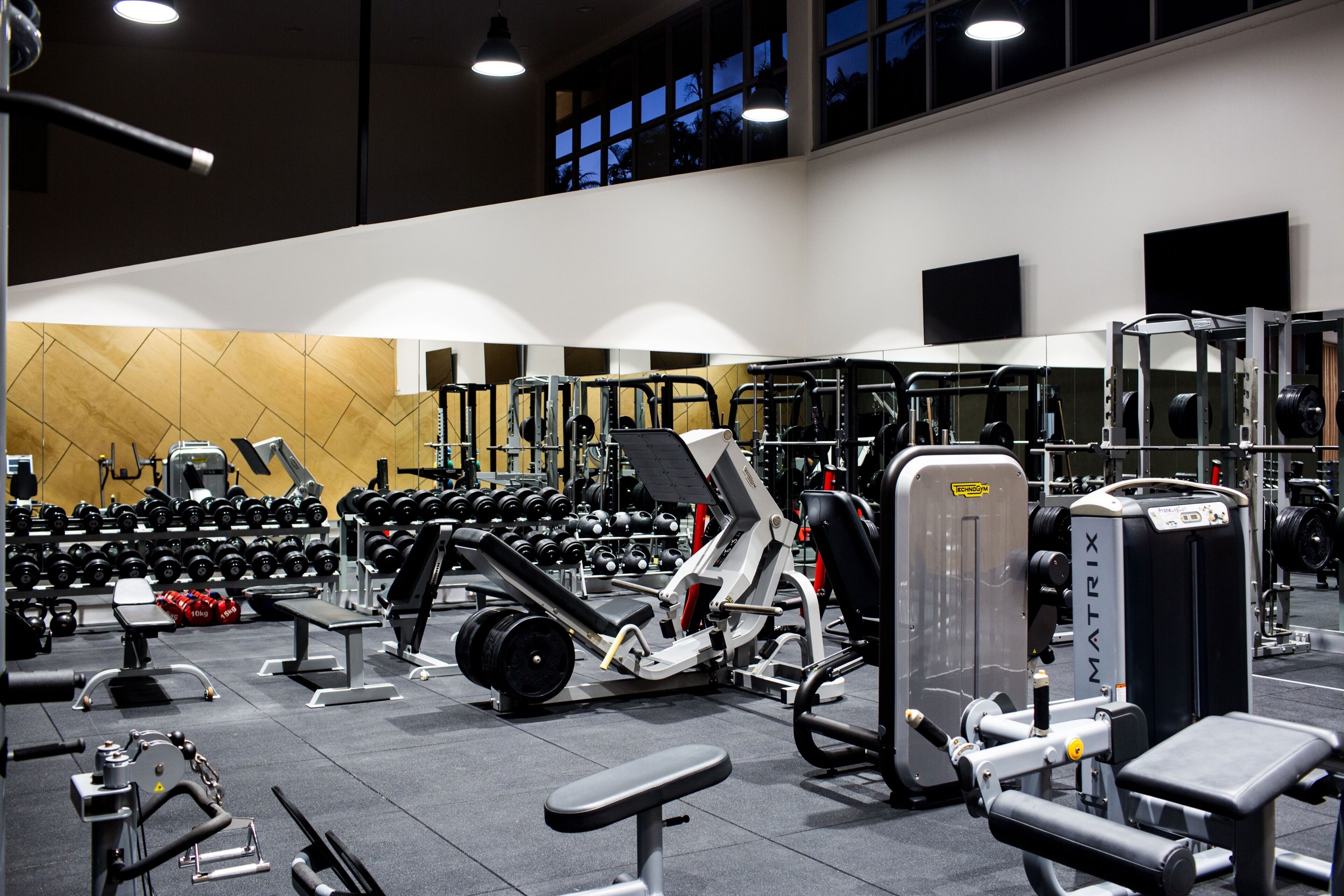 A gym with various exercise equipment, including dumbbells, benches, and weight machines.