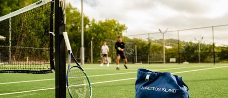 Un court de tennis avec un filet, une raquette de tennis et un sac sur lequel on peut lire « HAMILTON ISLAND ».