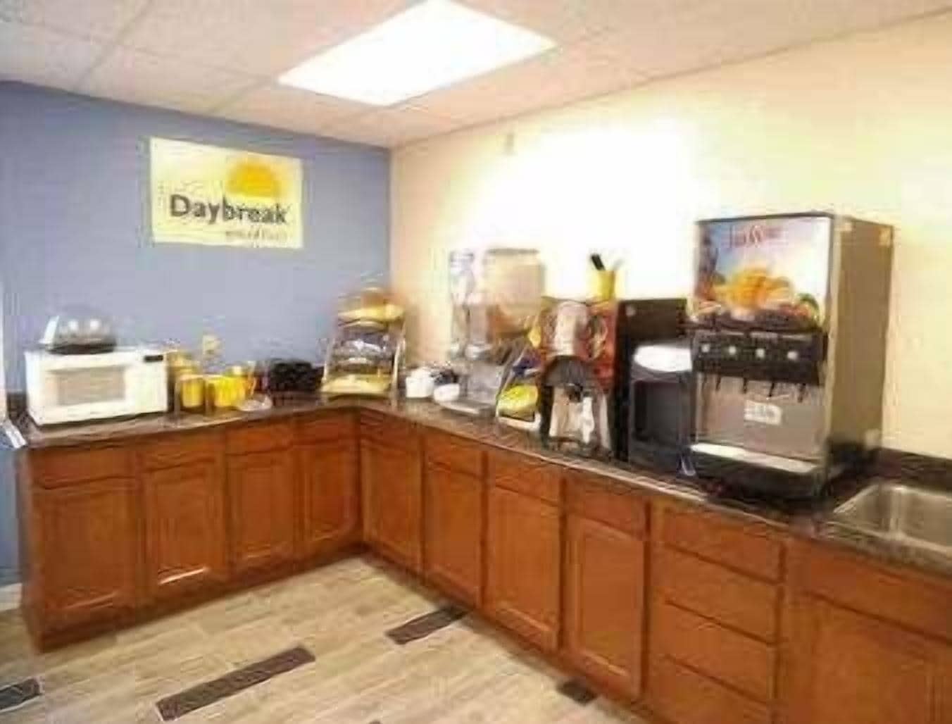 A kitchen with wooden cabinets, a microwave, a coffee machine, and a refrigerator.