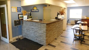 Un área de recepción con un mostrador de piedra, un cartel que dice "Days Inn" y un escritorio de recepción. Se ven sillas y una mesa al fondo.