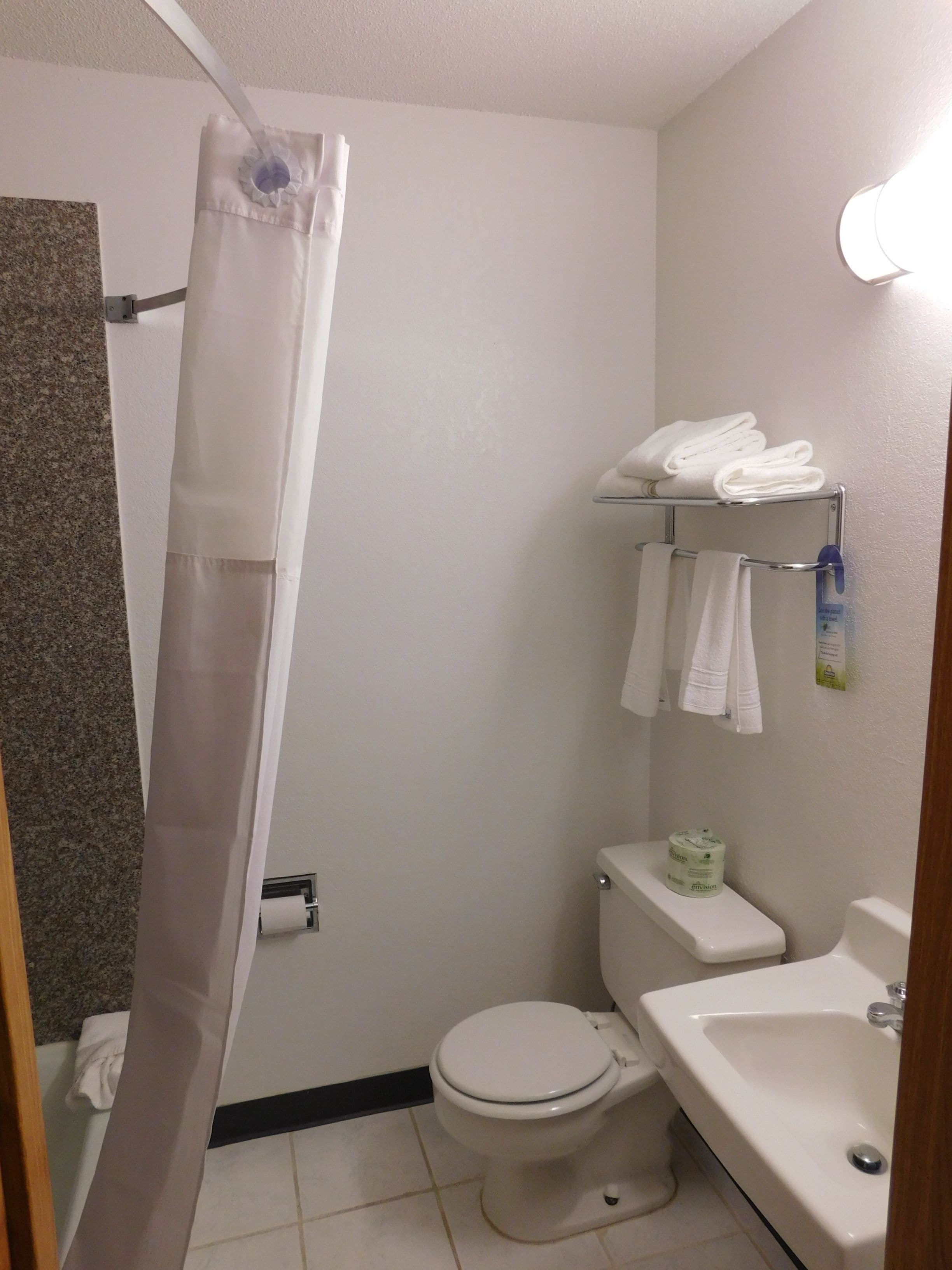 Une salle de bain équipée d’un rideau de douche, de toilettes, d’un lavabo et d’un porte-serviettes.