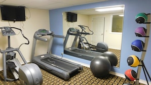 Un gimnasio con cintas de correr, elípticas y pelotas de ejercicio.