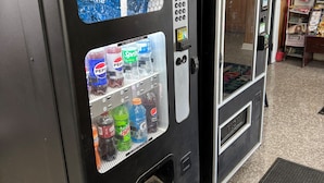 Máquina expendedora con un gráfico de salpicadura de agua, pantalla digital y una selección de bebidas, incluyendo Pepsi y Sprite.