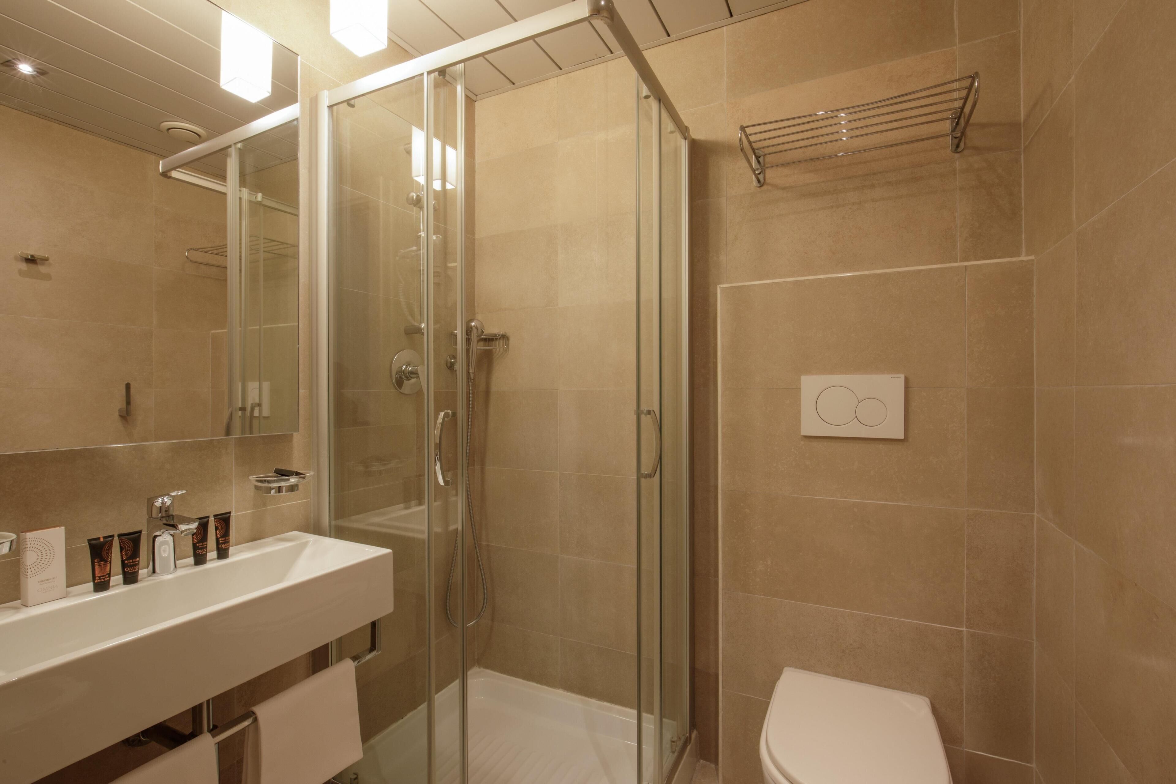 Een moderne badkamer met een douchecabine van glas, een witte wastafel en een toilet.