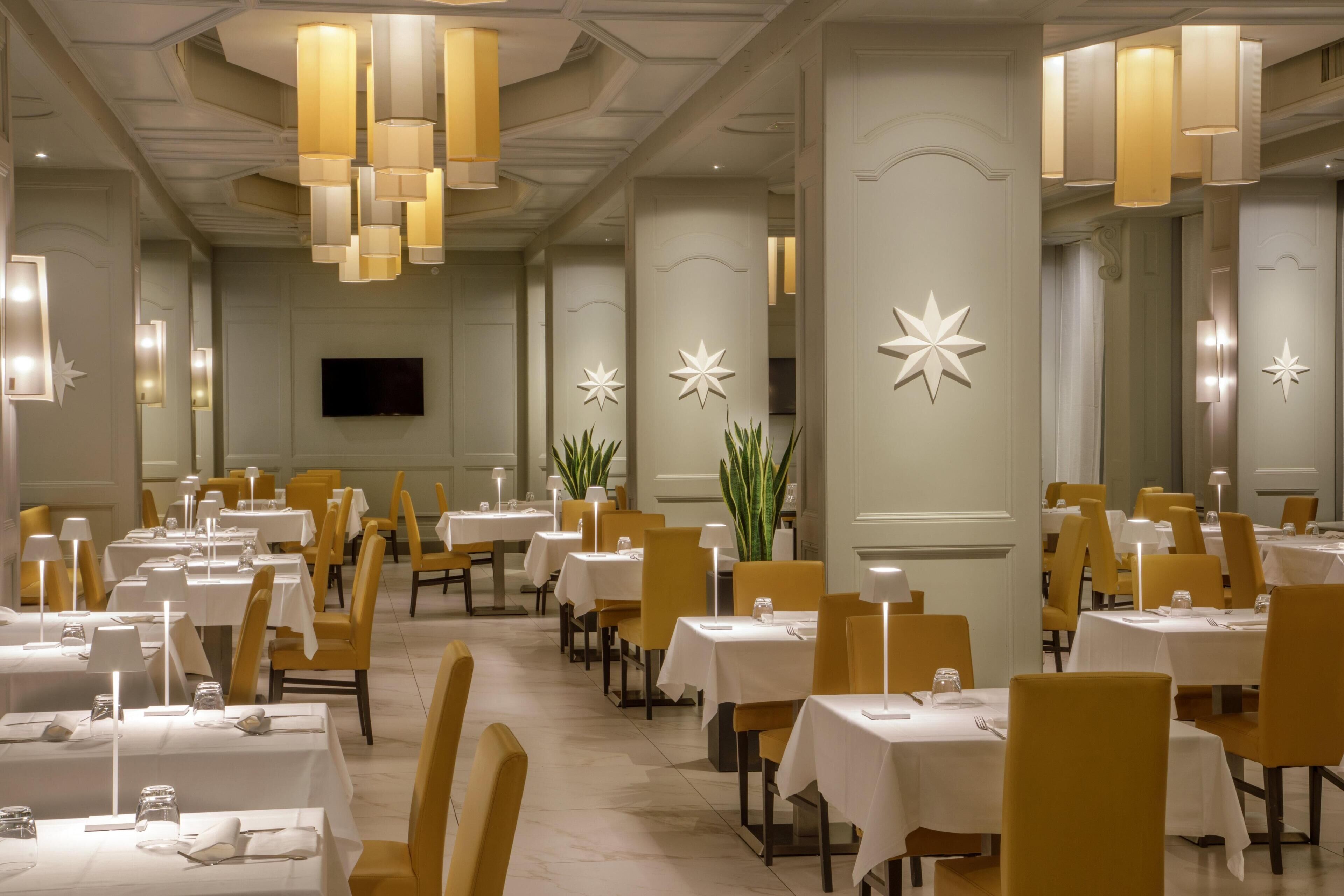 Ein Restaurant mit gedeckten Tischen, Deckenleuchten und dekorativen Wandelementen.