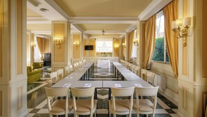 Un salón de conferencias con una mesa larga, sillas y una pantalla para presentaciones.