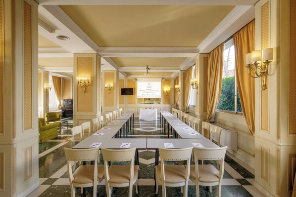 A conference room with a long table, chairs, and a presentation screen. - Grand Hotel Fleming by OMNIA hotels (Rome)