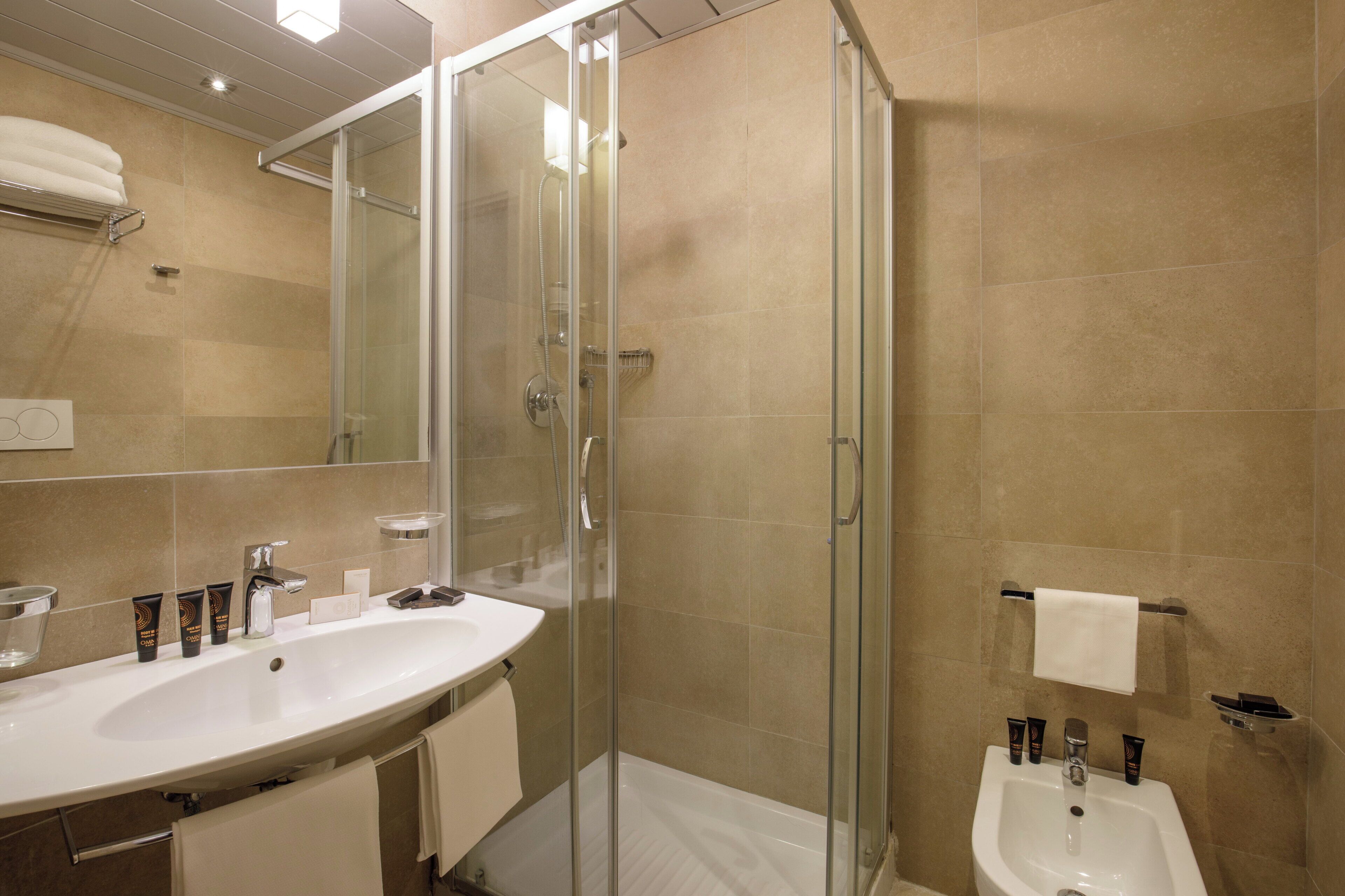 Ein modernes Badezimmer mit einer Glaskabine zur Dusche, einem großzügigen Waschtisch mit Becken und einem Spiegel.