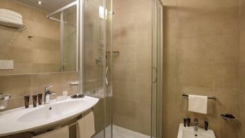 Ein modernes Badezimmer mit einer Glaskabine zur Dusche, einem großzügigen Waschtisch mit Becken und einem Spiegel.