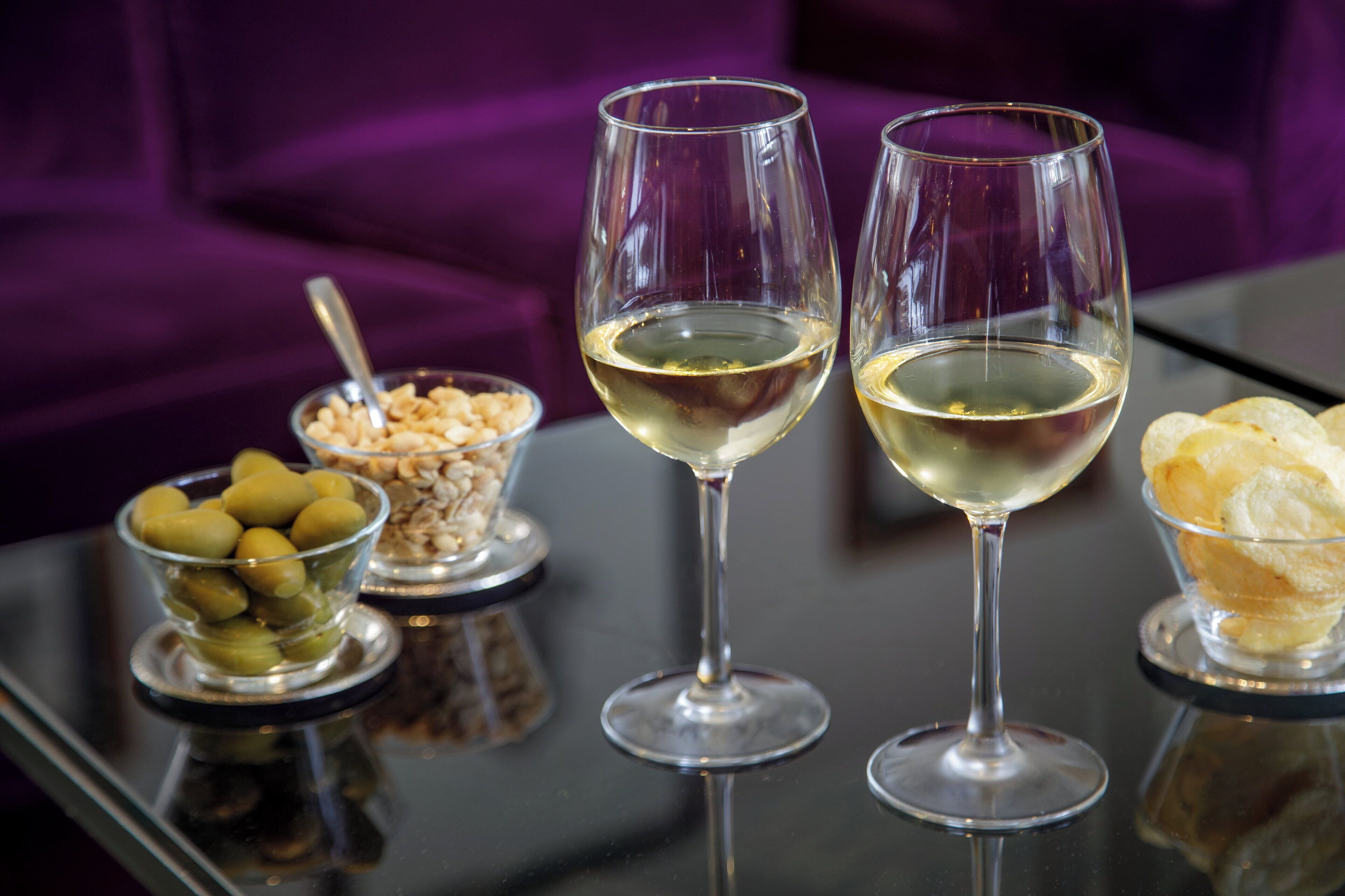 Three wine glasses on a reflective surface with a purple background.