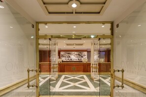A hotel lobby with a reception desk, glass doors, and a patterned floor. - Grand Hotel Fleming by OMNIA hotels (Rome)
