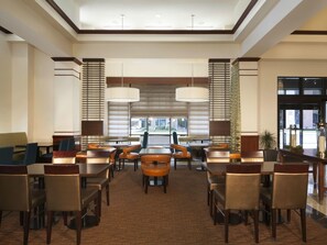 A spacious lobby with multiple seating areas, including tables and chairs, and large windows providing natural light. - Hilton Garden Inn Virginia Beach Town Center (Virginia Beach)