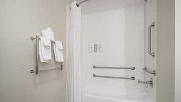 Un baño moderno con ducha, barras de apoyo, toallero y bañera.
