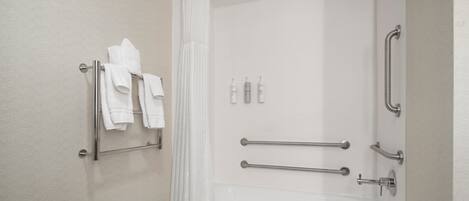 A modern bathroom with a shower, grab bars, a towel rack, and a bathtub.