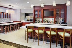 Una cocina moderna con barra, sillas de madera y un televisor de pantalla plana sobre la encimera.