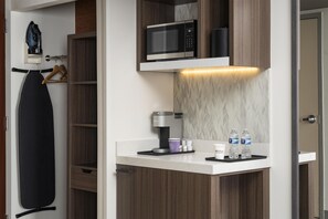 A compact kitchenette with a microwave, coffee maker, and water bottles. - Hilton Garden Inn Virginia Beach Town Center (Virginia Beach)