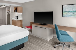 Een hotelkamer met een bed, een bureau met een televisie, een stoel, een magnetron en een kledingkast.