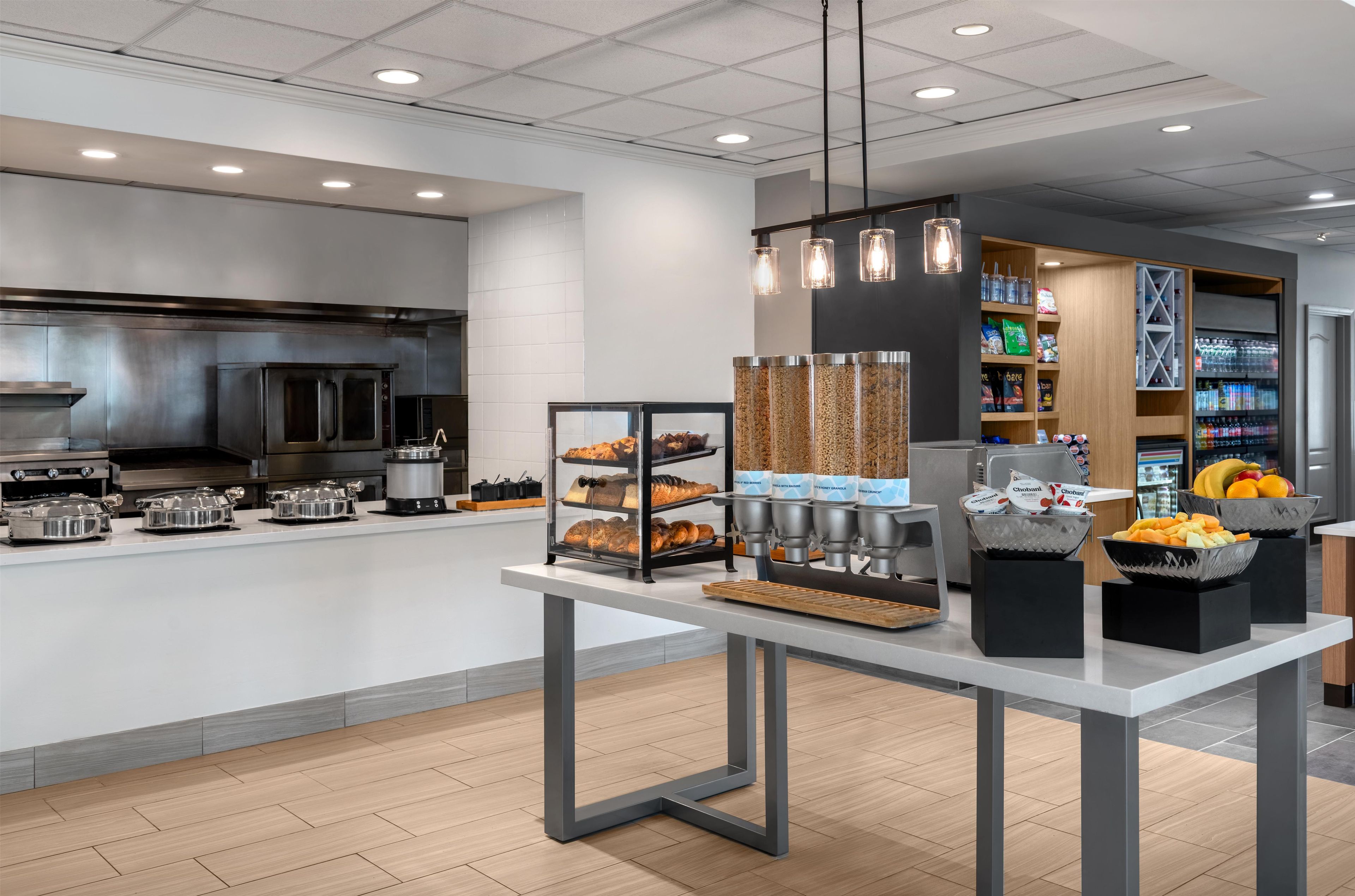 A modern kitchen area with stainless steel appliances, a buffet counter with various food items, and a beverage station.