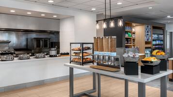Uma cozinha moderna com eletrodomésticos de aço inoxidável, um buffet com diversos alimentos e um espaço para bebidas.