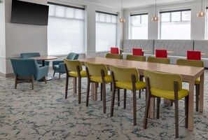 Une salle de conférence avec une longue table, de nombreuses chaises et un espace détente avec des fauteuils rouges.