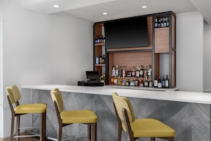 A bar area with a counter, a flat-screen TV, and a variety of liquor bottles. - Hilton Garden Inn Hartford South/Glastonbury (Glastonbury)