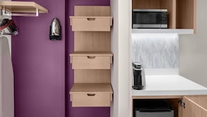 A kitchen with a microwave, coffee maker, and cabinets.