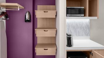 A kitchen with a microwave, coffee maker, and cabinets.