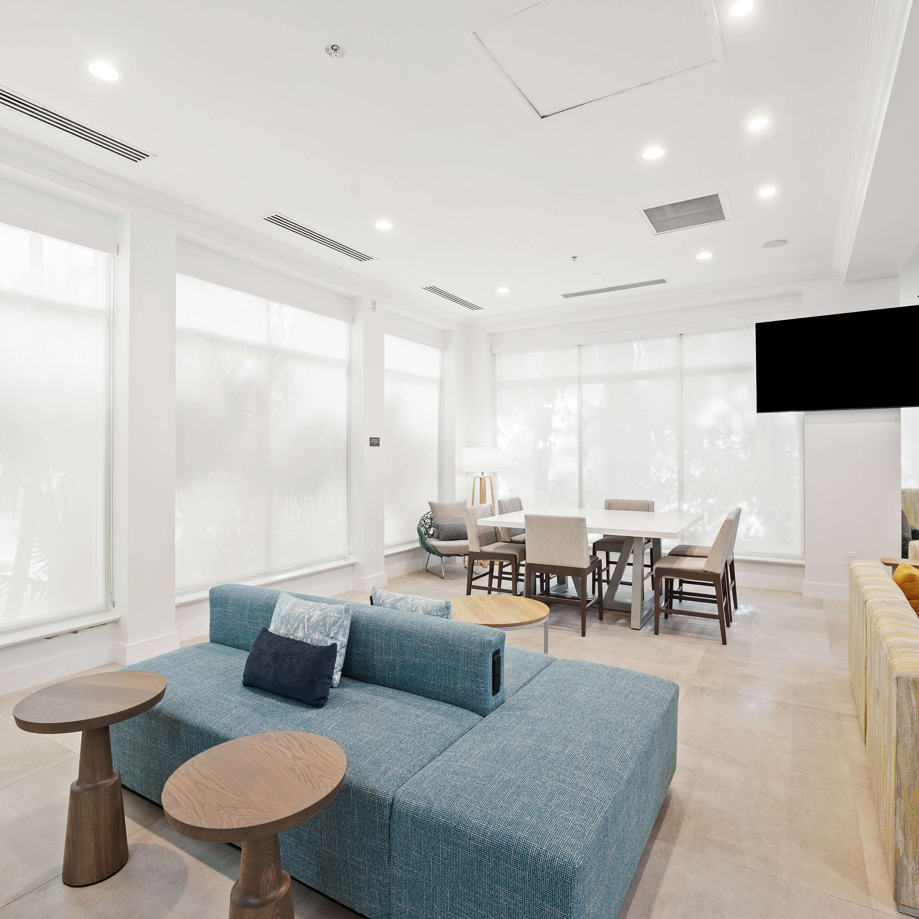 Una sala de estar moderna con un sofá azul, una mesa de centro redonda y un comedor con sillas y una mesa.