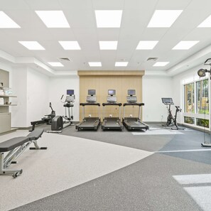 A modern fitness center with treadmills, stationary bikes, and a bench. - Hilton Garden Inn Fort Lauderdale Airport-Cruise Port (Dania Beach)