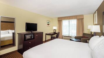 A hotel room with a bed, a desk, a television, a chair, and a window with curtains.