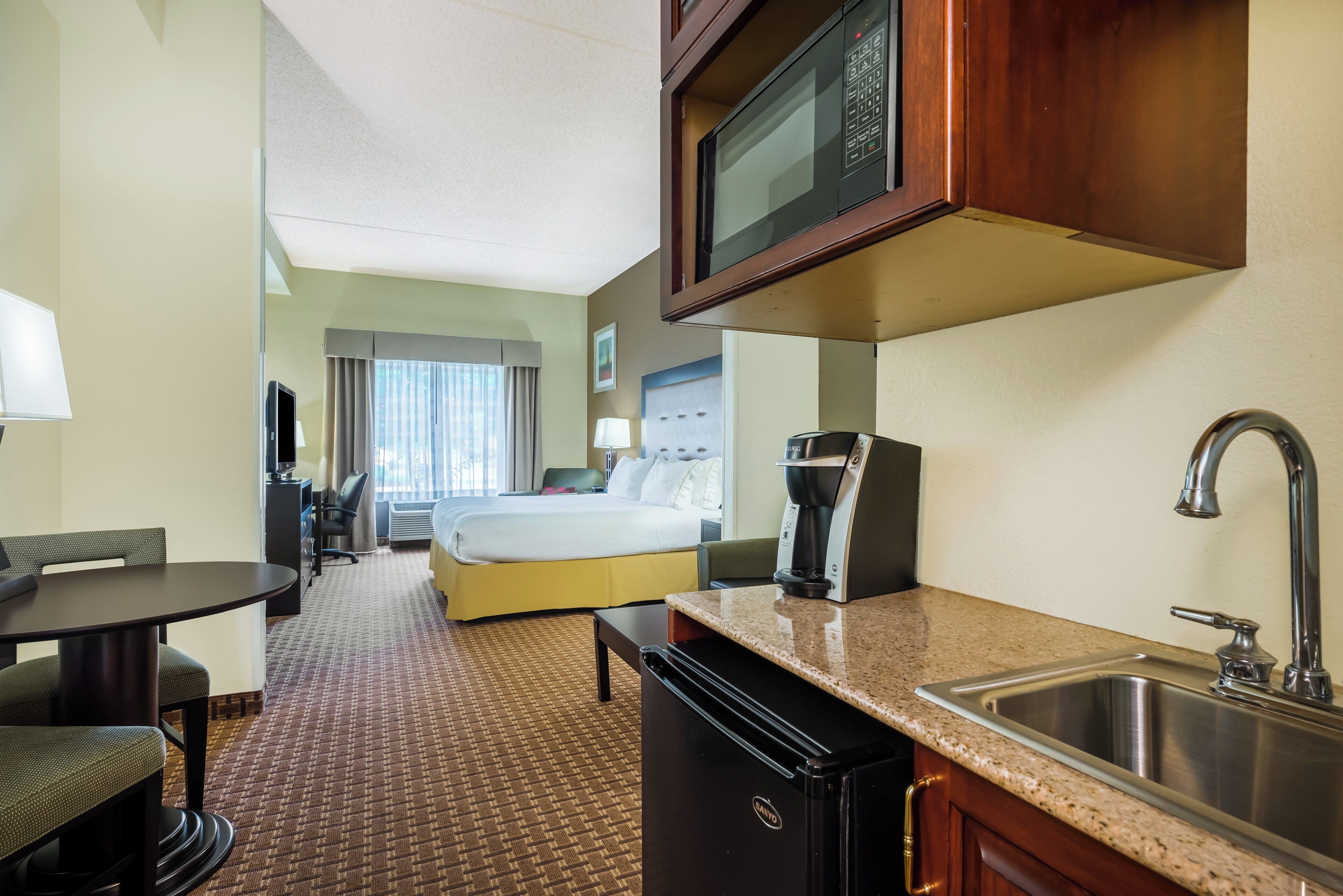 Hotelkamer met een bed, bureau, koffiezetapparaat, magnetron en wastafel.