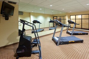 A gym with treadmills and an exercise bike, a television on the wall, and a patterned carpet. - Holiday Inn Express North East by IHG (North East)