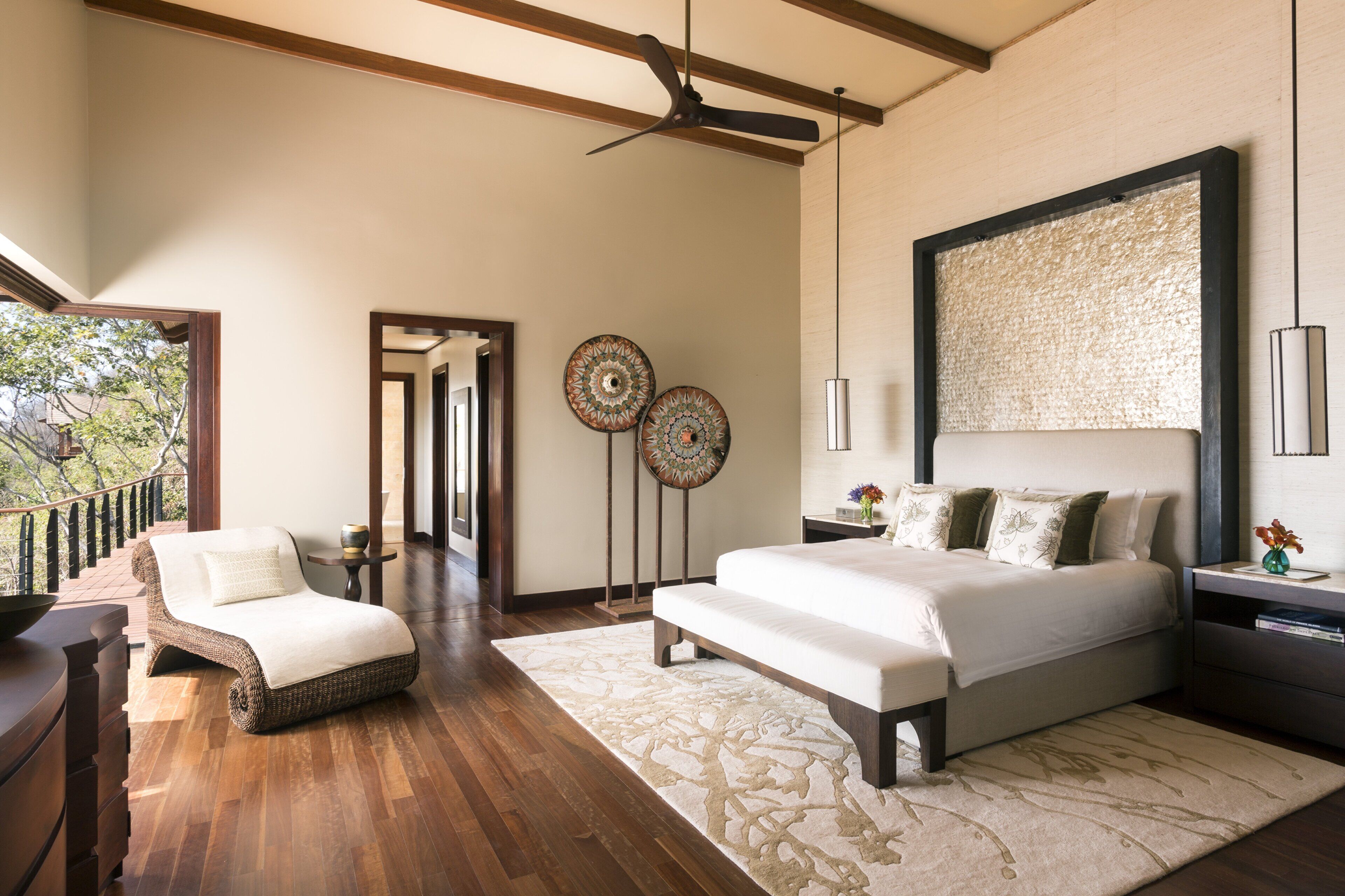 Un dormitorio con una cama grande, un chaise lounge, un ventilador de techo y vistas al exterior.