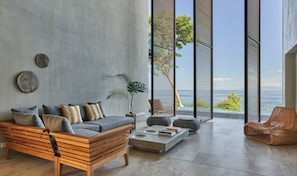 A modern living room with a sofa, coffee table, and a view of the ocean.