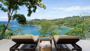 A balcony with two wicker lounge chairs, a small table, and a wicker basket. - Four Seasons Resort Peninsula Papagayo, Costa Rica (Nacascolo)