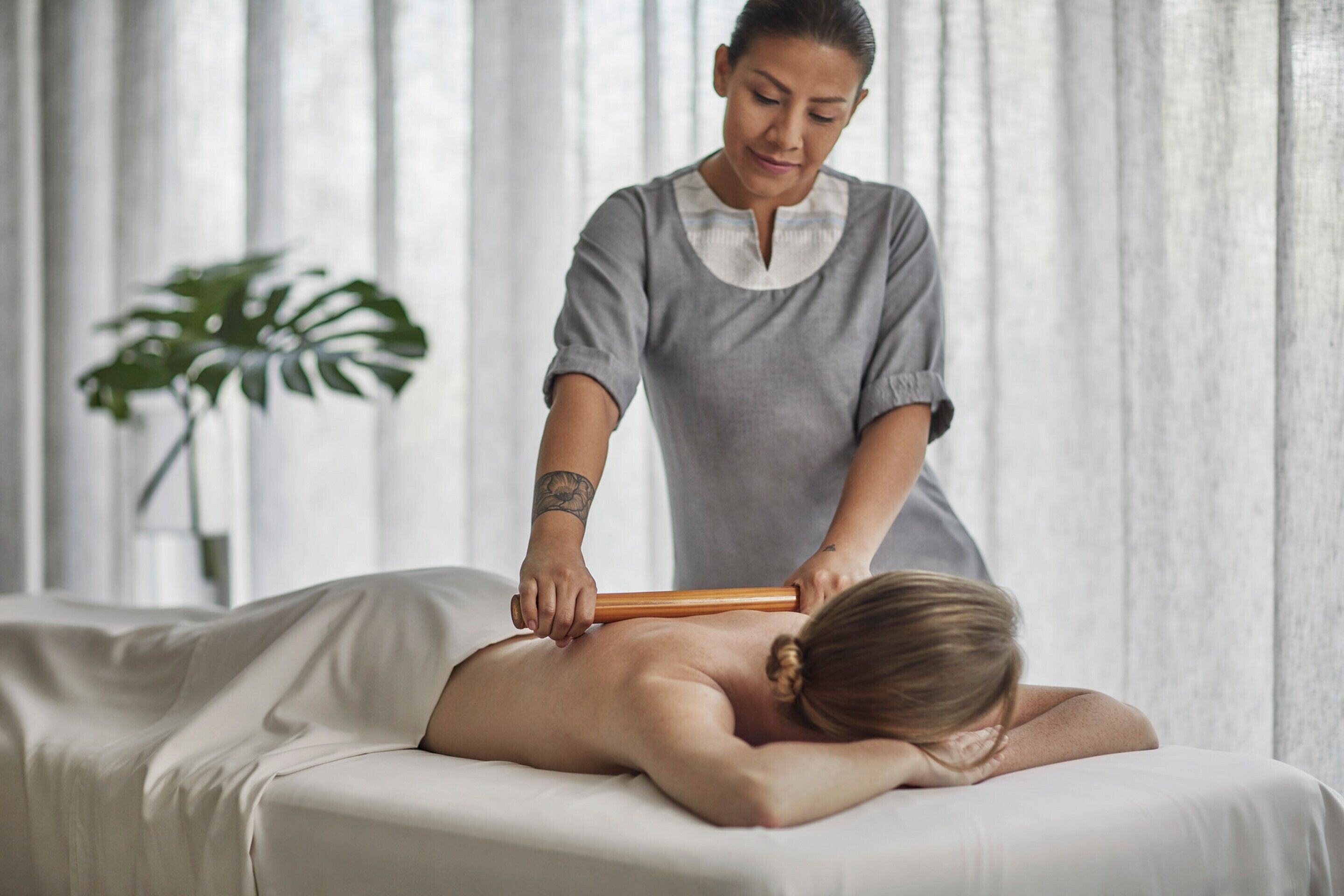 A massage therapy session in a room with a large window and a plant.
