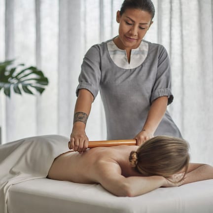 A massage therapy session in a room with a large window and a plant.