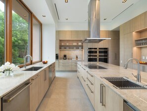 A modern kitchen with a large island, stainless steel appliances, and wooden cabinetry.