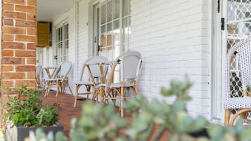 A covered outdoor seating area with wicker chairs and a brick wall.