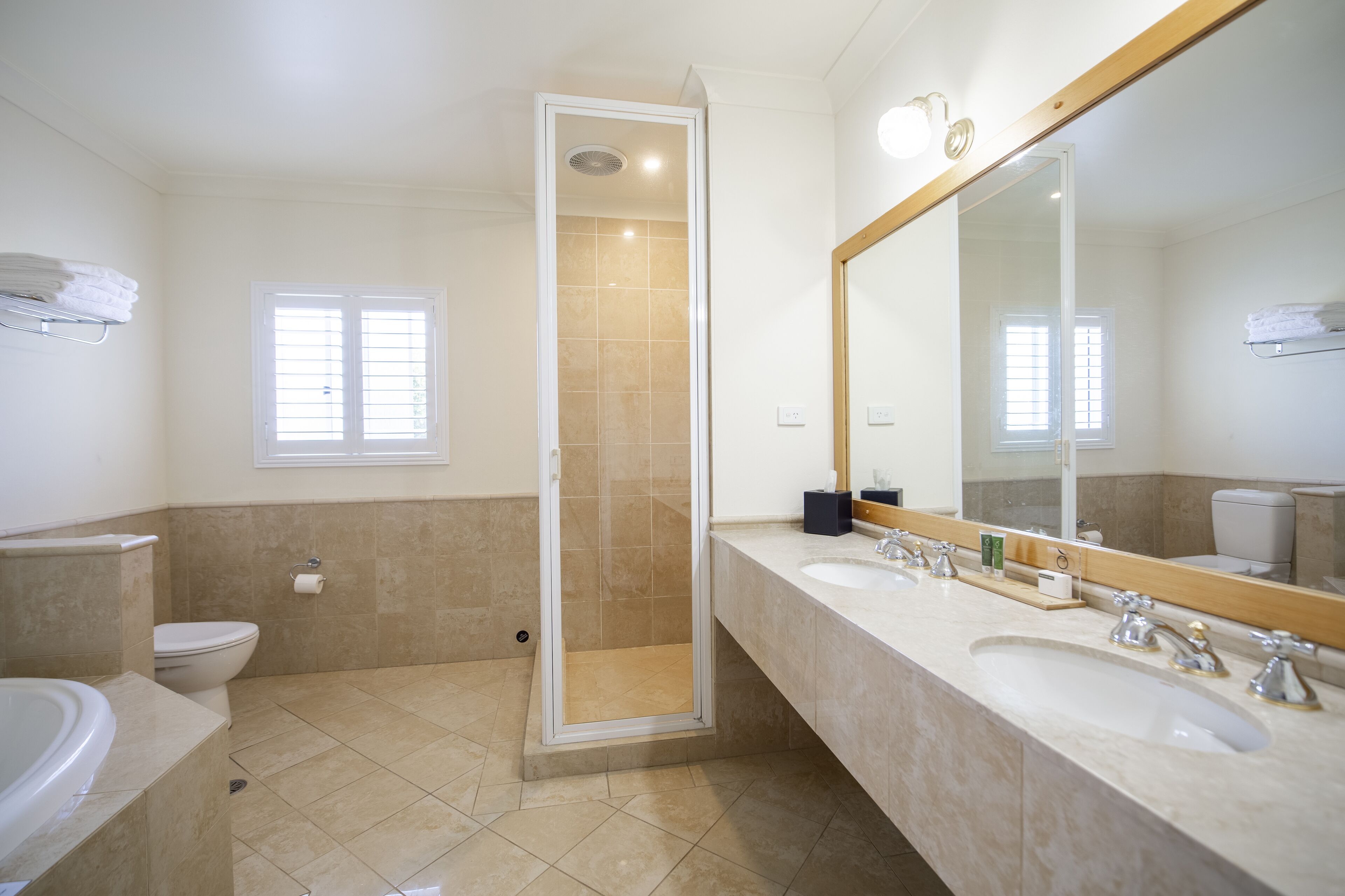A modern bathroom with two sinks, a toilet, a shower, and a large mirror.