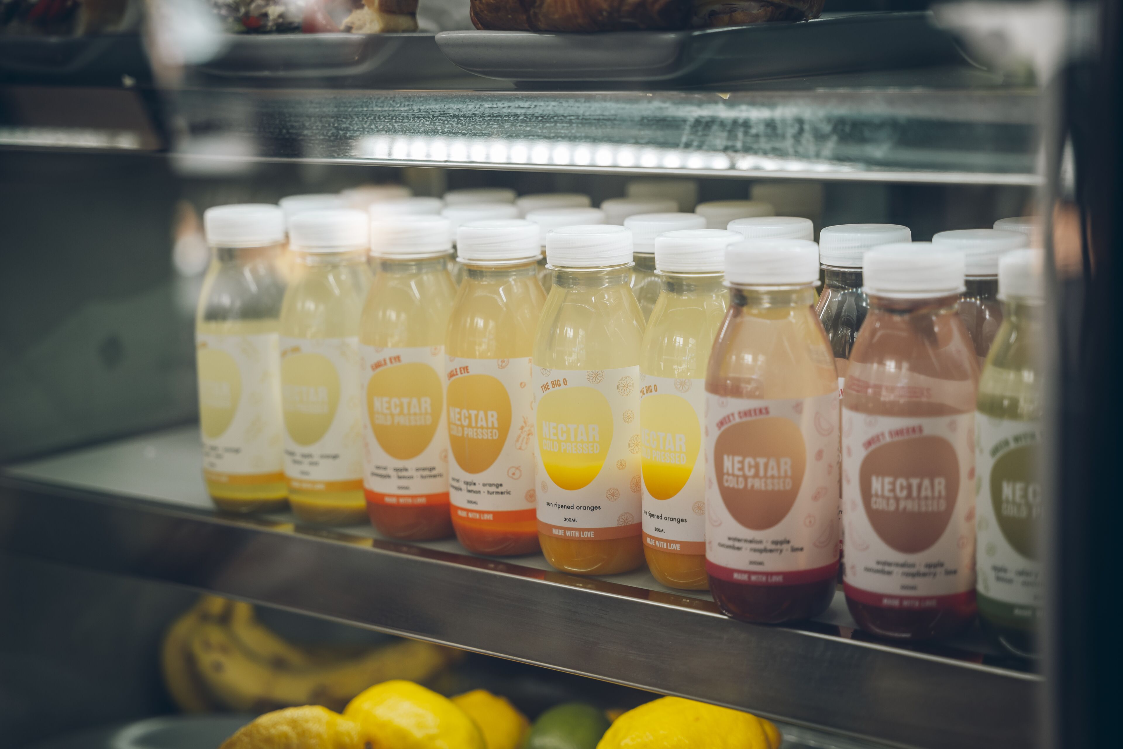 A refrigerated display case with bottles of nectars in various flavors.