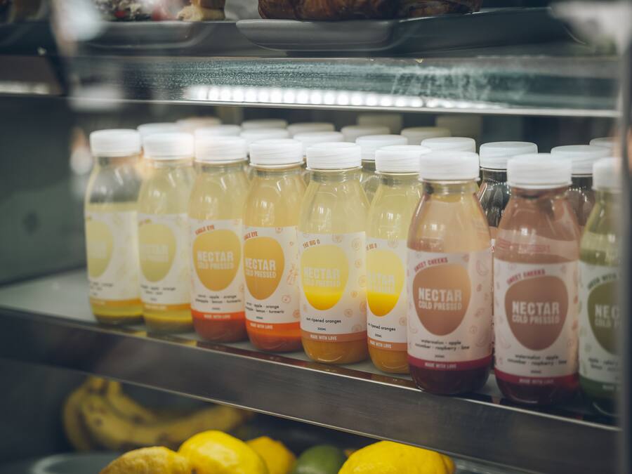 A refrigerated display case with bottles of nectars in various flavors.