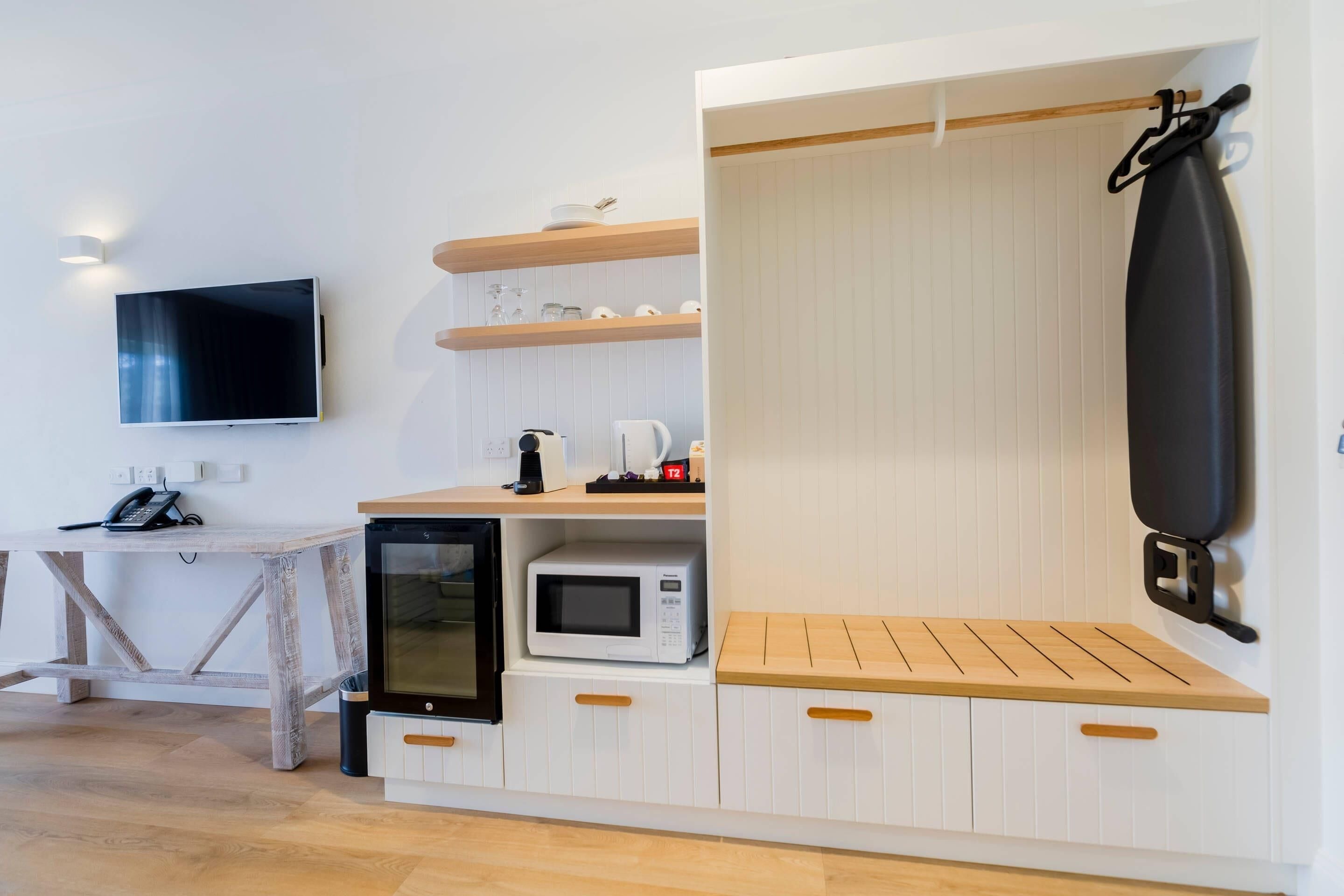 Eine kompakte Küchenzeile mit Mikrowelle, Kaffeemaschine und kleinem Kühlschrank.