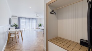 Una habitación moderna y luminosa con un banco de madera, un perchero y una zona de comedor con mesa y sillas.