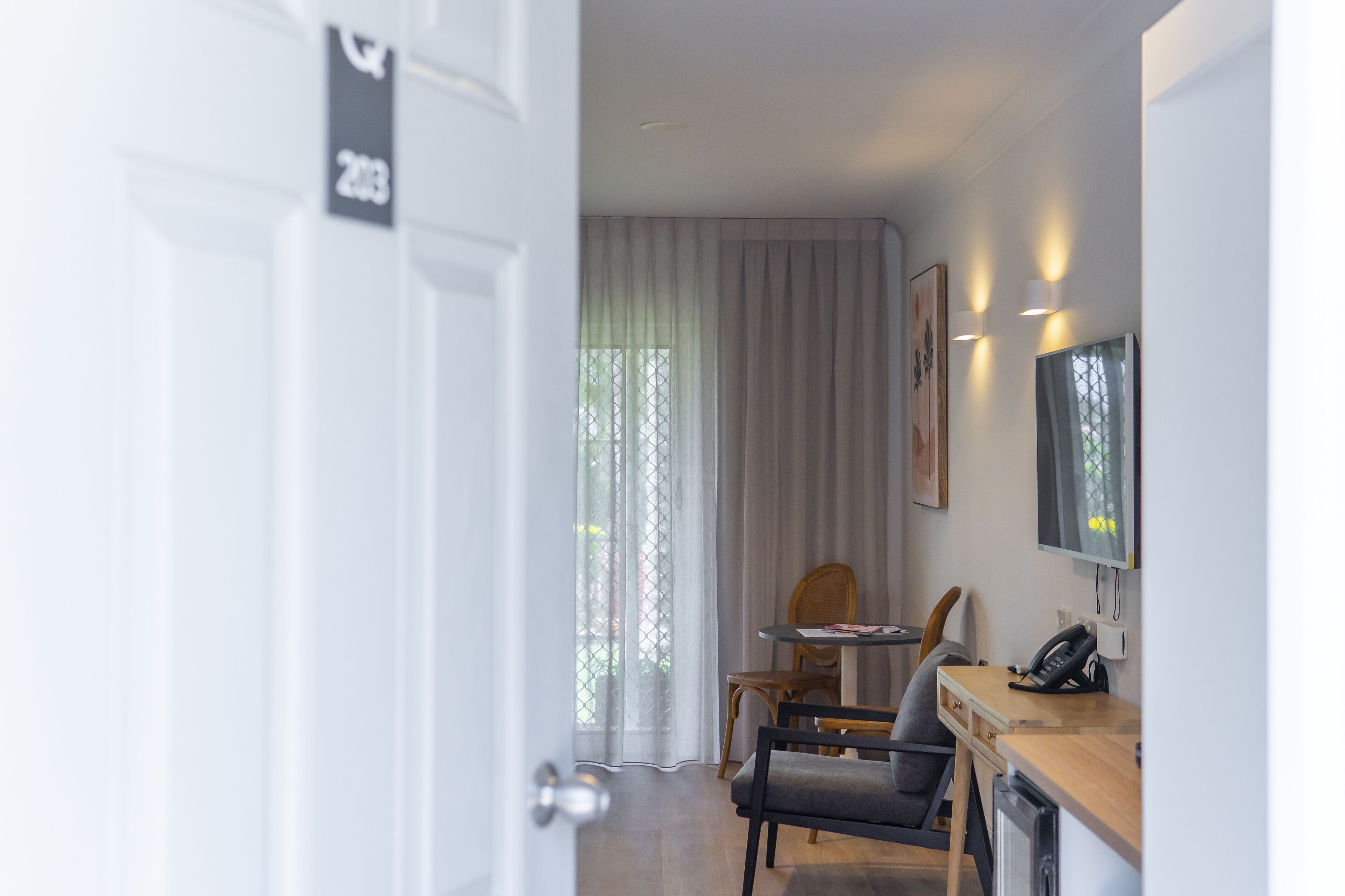 Une chambre d’hôtel moderne équipée d’un coin repas, d’un téléviseur et d’une porte portant un numéro.