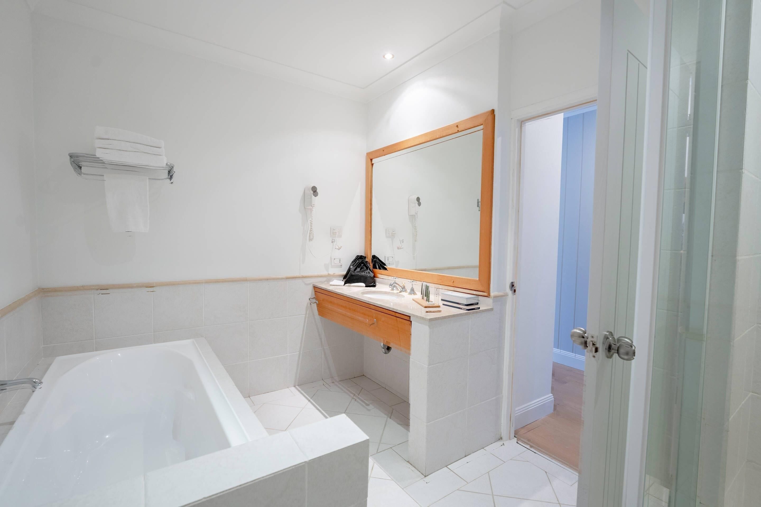 A bathroom with a bathtub, a vanity with a mirror, and a shower area.